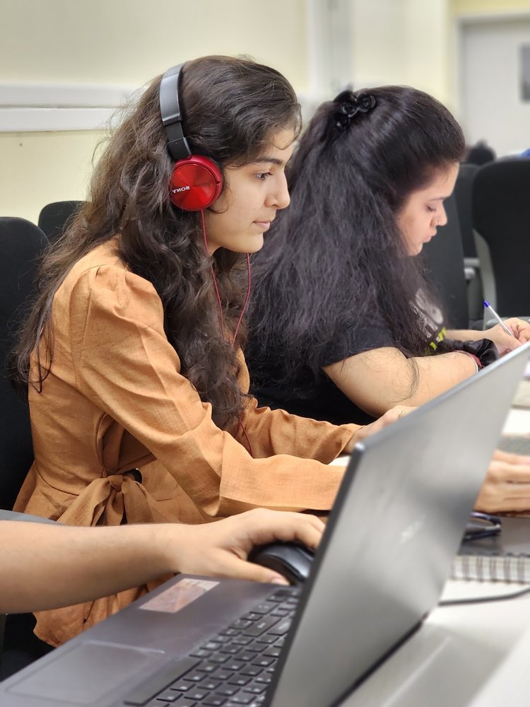 Diya with headphones at a laptop
