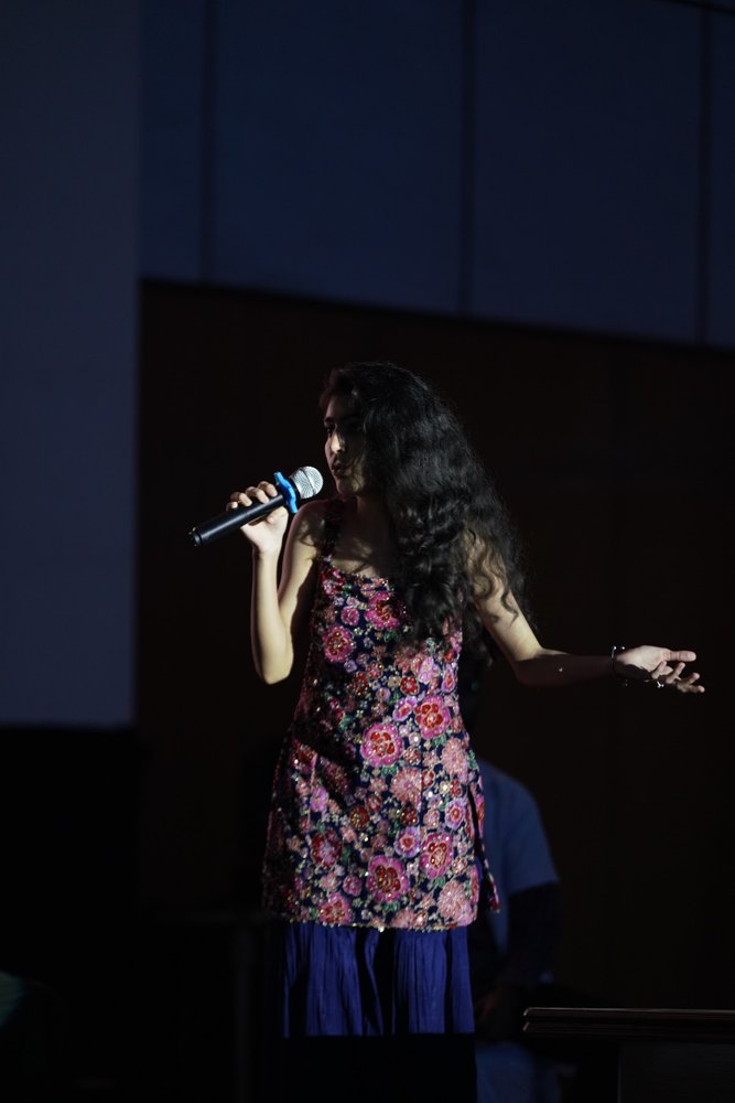Diya performing on stage with a microphone